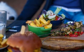 Bakje friet op tafel. Ernaast een spiesje met vlees. 