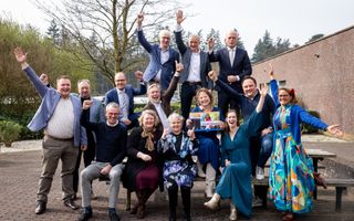 Groepsfoto met juichende mannen en vrouwen. In het midden vrouw met een cheque met het eindberag van de actie. 