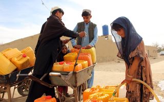 Enkele mensen tappen water uit oranje jerrycans.