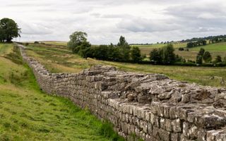 Muur van ongelijke stenen golft door een heuvelachtig landschap.