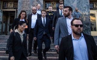 Een groep mensen, mannen in pak, loopt van een marmeren trap af.