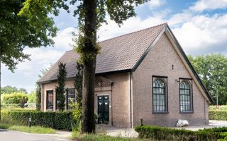 Kerkgebouw met schuin dak in groene omgeving.