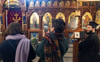 Jonge mensen maken met hun telefoon foto’s van iconen in de iconostase van de Grieks-orthodoxe kerk in Utrecht.
