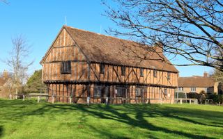 Een oud pand, met schuine balken in de buitenmuren. Eromheen gras.