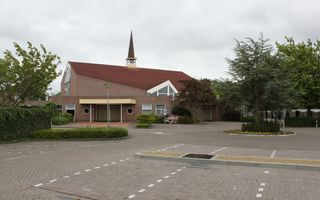 Kerkgebouw met een parkeerplein ervoor.