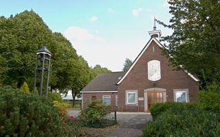 Bakstenen kerkgebouw met klein wit torentje.