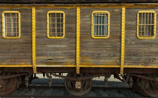 Treinwagon van horizontale planken. De metalen delen zijn frisgeel geschilder.