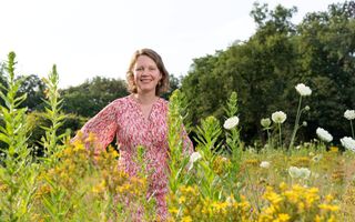 Een vrouw met een roze jurk aan in een veld met gele bloemen.