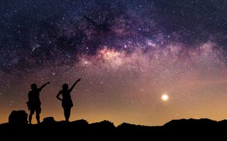 Twee kindersilhouetten wijzen naar een paars-oranje-gele sterrenlucht.