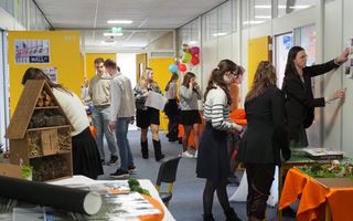 Een gang met leerlingen. Op een tafel een maquette van een groen schoolplein en een insectenhotel.