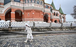 Een vrouw in witte kleding loopt langs een bakstenen kerk.