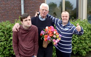 Cliënten Andre Imanse (l.) en Gertjan de Leeuw van Wenen (r.) van Siloah in Bodegraven geven vrijwilliger Henk van Holst (m.) een bos bloemen. beeld Dijkstra BV
