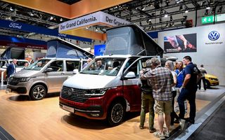 Mensen staan bij een grijze en een wit-rode versie van een camper met hefdak.