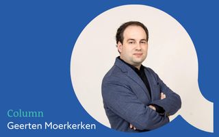 Een man met donker haar, een zwarte bloes en blauw jasje met zijn armen over elkaar. Hij is geprojecteerd in een witte cirkel op een blauwe achtergrond.