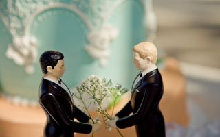 Twee poppetjes, mannetjes, staan in deftg zwart pak tegenover elkaar met bloemen.