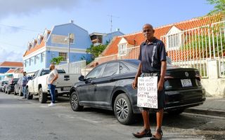 Een man met een rafelige kniebroek met een protestbord.