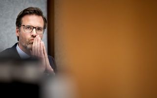 Man zit met handen tegen elkaar voor zijn mond. 