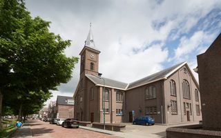 Een kerk met een torentje aan een  rustige straat.