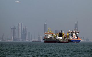 Schepen liggen in het water voor wolkenkrabbers. 