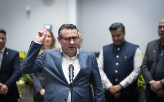 Richard de Mos legt de eed af. Hij draagt een blauw pak, een wit overhemd en staat voor een microfoon. 