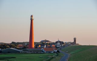 Vuurtoren aan de rand van een dorpje aan zee.