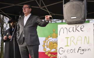 Een man achter een luidspreker. Naast hem een pamflet met daarop onder meer: Make Iran Great Again  (Maak Iran Weer Groot)