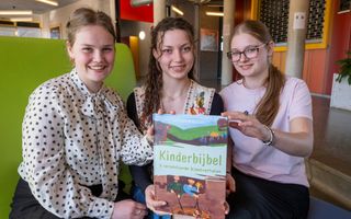 Drie leerlingen houden hun profielwerkstuk, een kinderbijbel, vast.