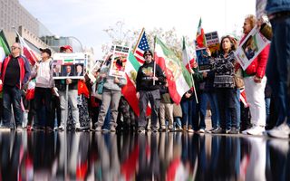 Mensen houden Iraanse en Amerikaanse vlaggen vast. 