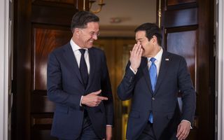 Twee mannen in pak smoezen lachend met elkaar terwijl ze uit een grote deur lopen. 