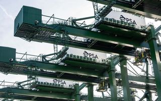 Closeup van vijf grote, groene scheepskranen tegen een blauwgrijze lucht.