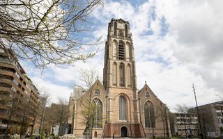 De hoge, markante toren van de Laurenskerk, met een wat afgestompte bovenkant. Aan weerszijden van het kerkgebouw appartementencomplexen.