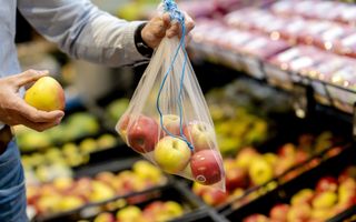 Een man houdt een verszak met appels vast.  