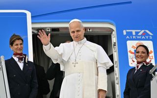 Paus Leo, een man in het wit gekleed, zwaait bij een blauw vliegtuig.
