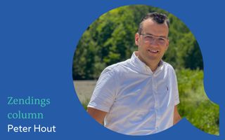 Man met golvend zwart haar, montuurloze bril, glimlach, wit overhemd met korte mouwen.