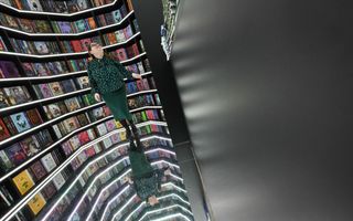 En vrouw staat voor een boekenkast.