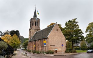 Een oude kerk met een toren. Bovenop de Oekraïense vlag.
