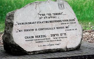 Een grijze steen met zwarte letters erop.
