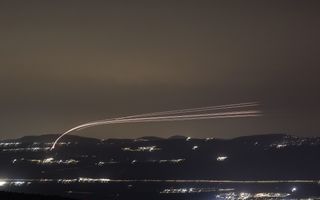Lichtspoor langs donkere hemel boven heuvellandschap.