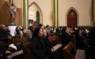 Kerkgebouw met mensen in vooral zwarte kleding, zittend op banken.
