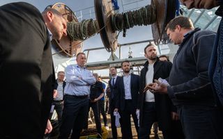 Enkele mannen zijn met elkaar in gesprek op het dek van een viskotter.