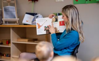 Een peuterleidster leest voor uit een prentenboek.