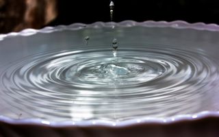 Waterdruppels vallen in een schaal gevuld met water.