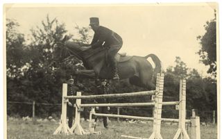 Zwart-witbeeld van een donker, springend paard over een witte hindernis