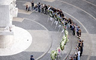 Kinderen in een halfronde cirkel leggen bloemen op de grond.