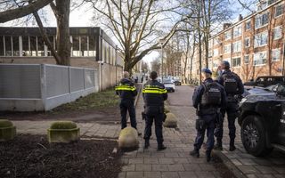 Twee agenten en twee marechaussees naast een ijzeren hek met punten erop.