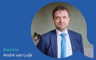 Man in een blauw pak. Hij draagt een wit overhemd en een lichtblauwe stropdas.