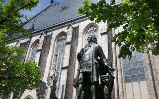 Een standbeeld van Johann Sebastian Bach staat voor een kerk in Leipzig.