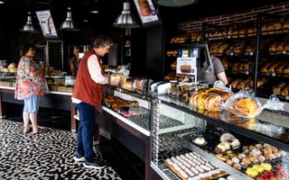 Twee klanten in een bakkerij willen afrekenen in een donkere winkel.
