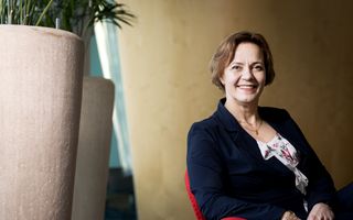 Donker geklede en lachende vrouw van middelbare leeftijd met kort haar.