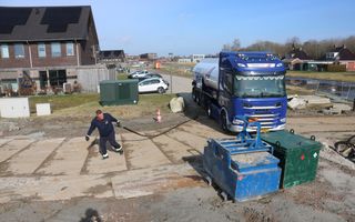 Een man sleept met een slang die uit een vrachtwagen komt.